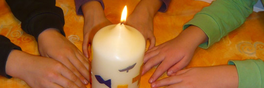 Kinderhände um eine Kerze